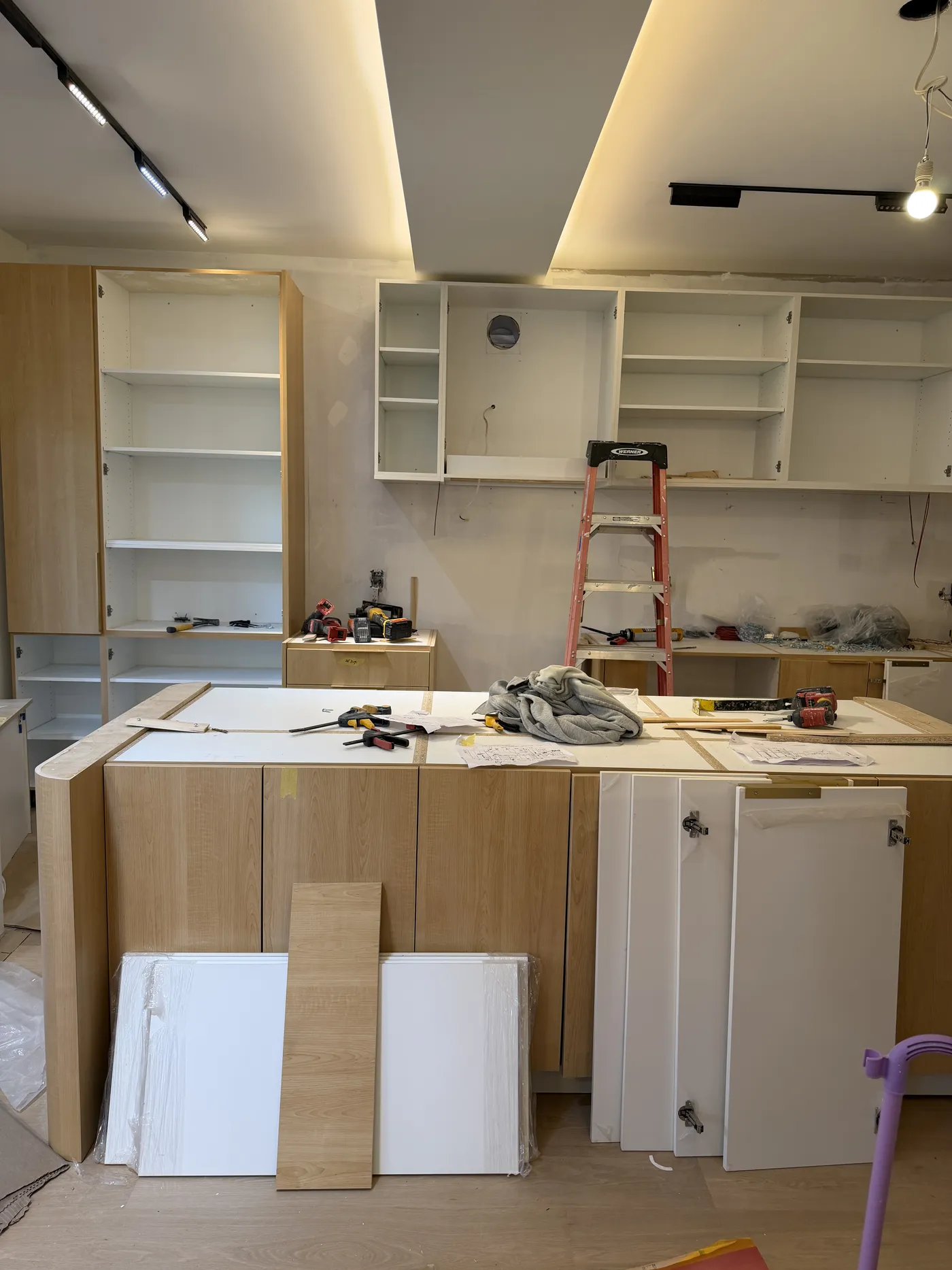 The kitchen mid-build: oak and white cabinets going in around a new island.