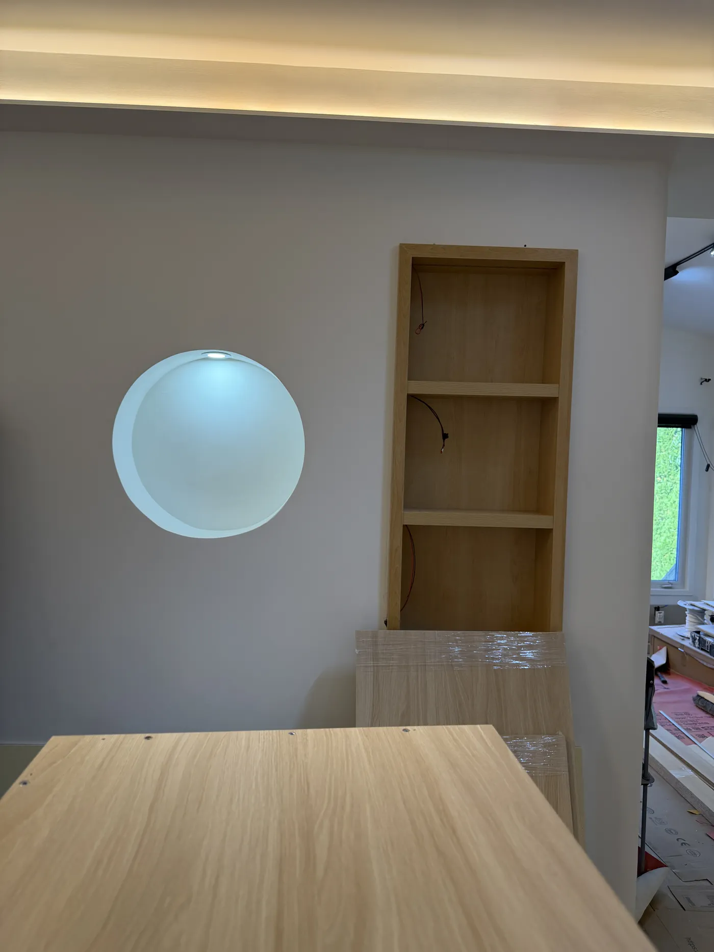 The round niche and oak shelf, built and lit.