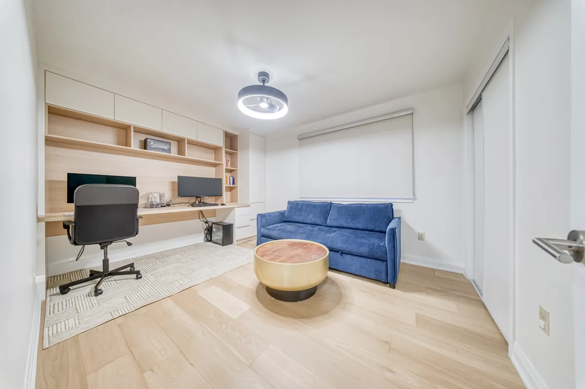 A home office with a built-in oak desk and shelving along one wall.